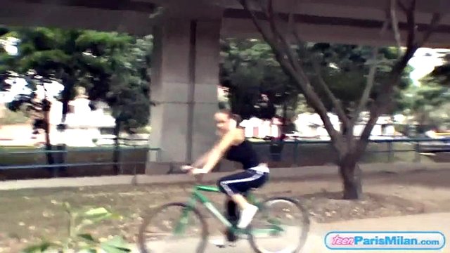 Adolescente tettona solista in sella alla sua bicicletta attraverso il parco